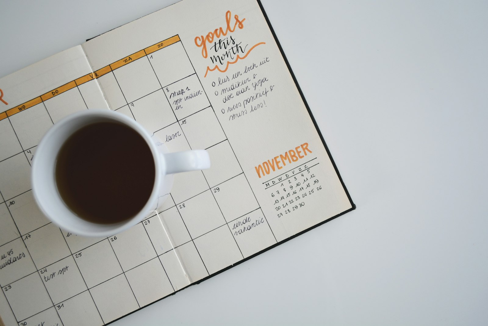 An open monthly planner showing a dated grid and a coffee cup, used to schedule a fixed close calendar