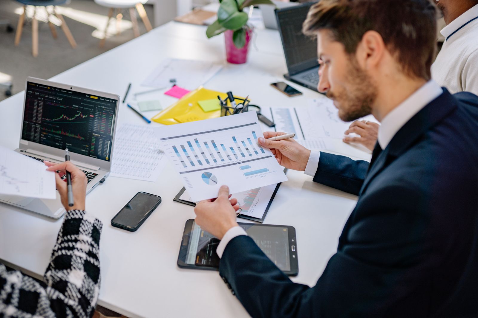 A finance professional reviewing printed financial charts and reports at an office desk