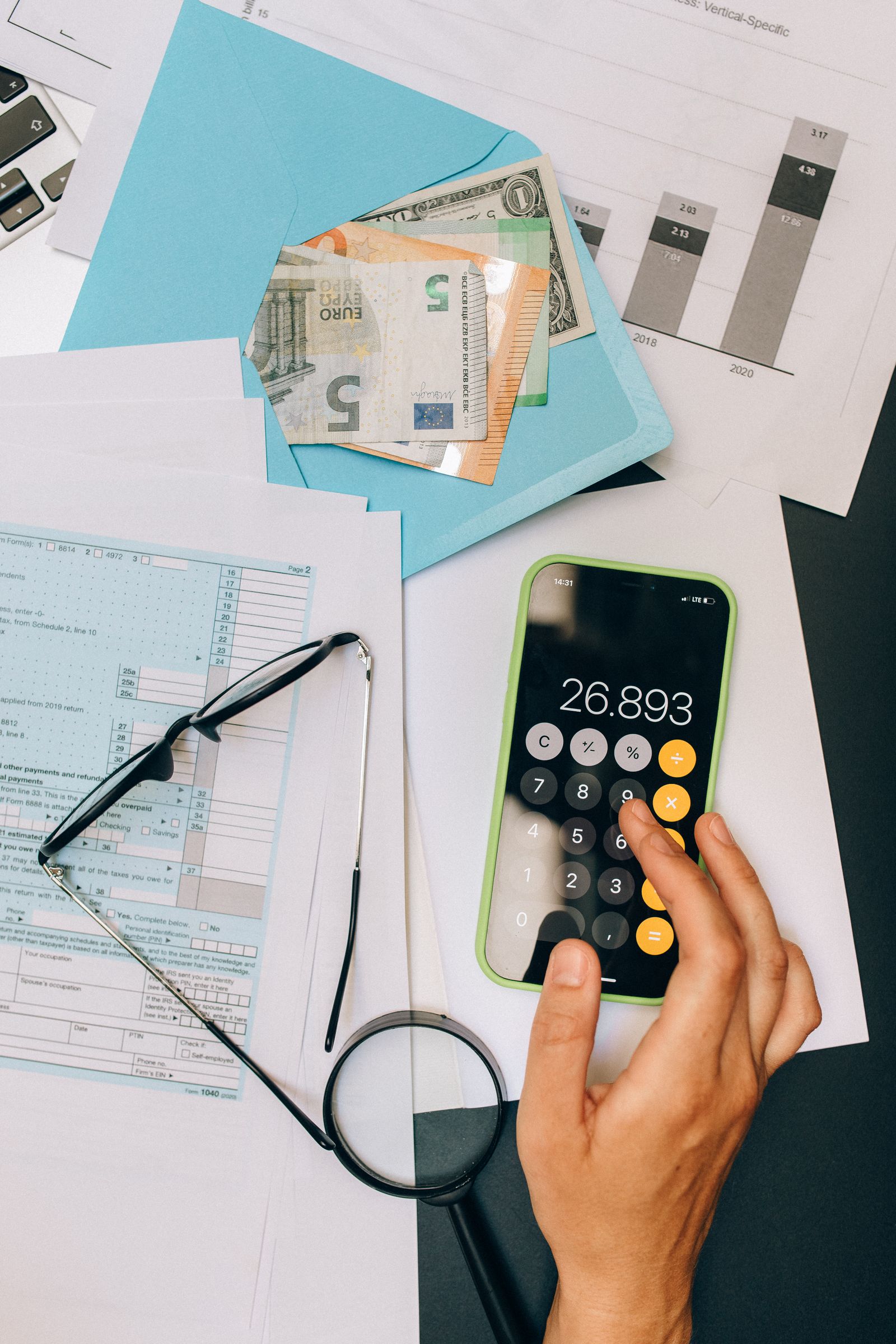 Form 1040 page beside reading glasses, a magnifier, and a calculator during return review