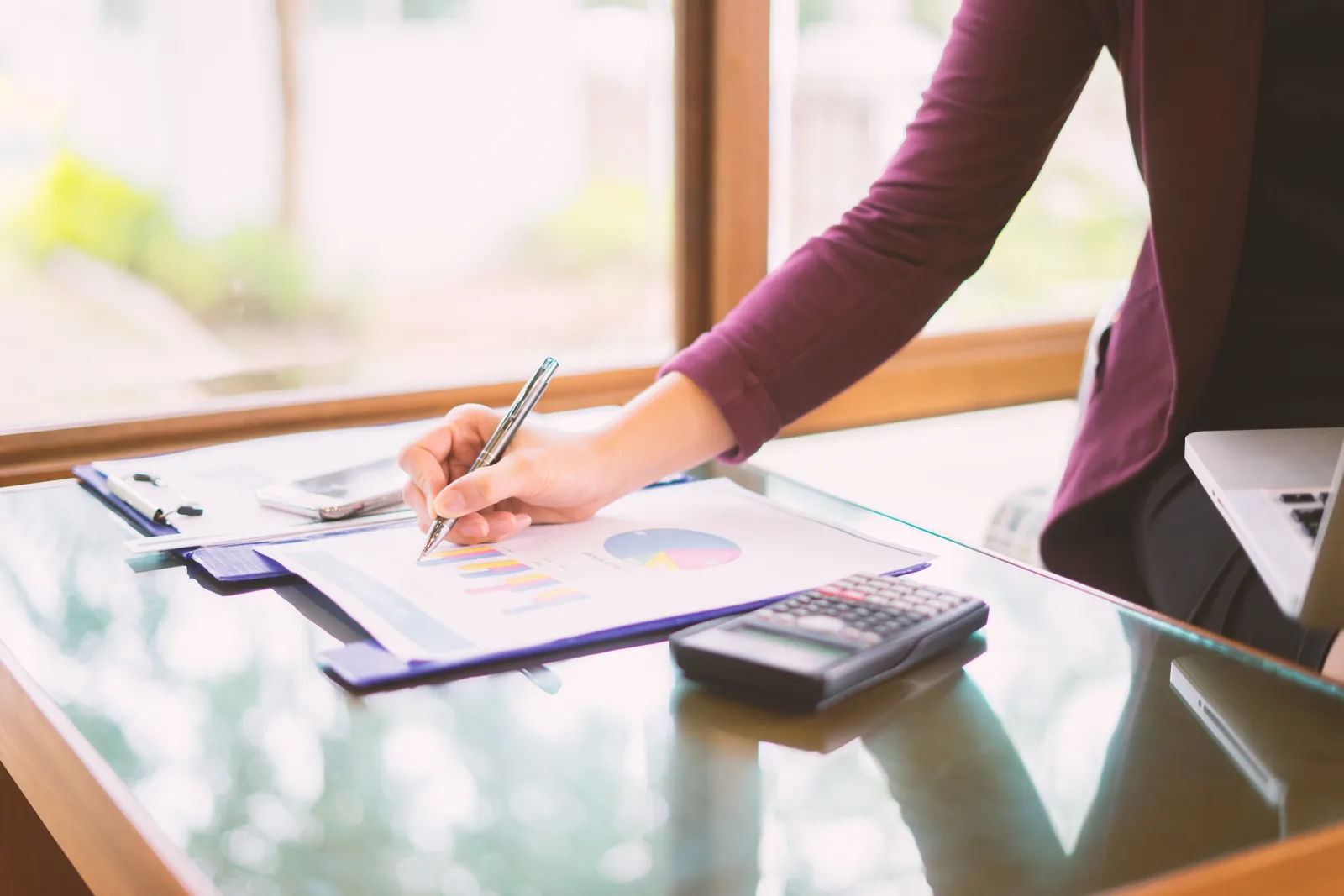 Accountant marking up a financial report beside a calculator while reviewing vendor costs at month end