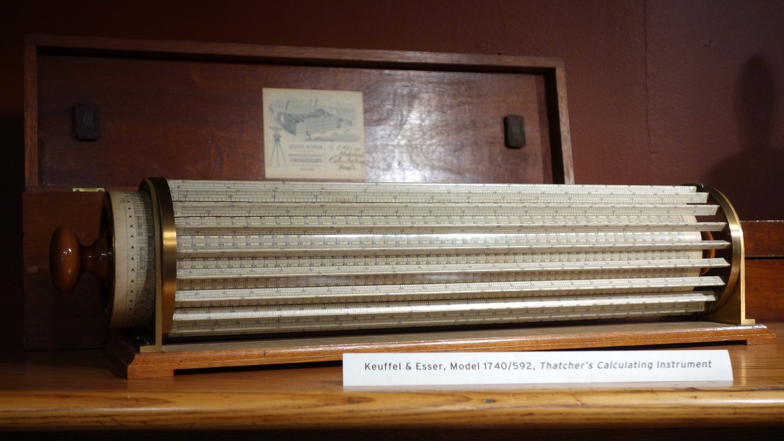 Keuffel & Esser Thatcher's Calculating Instrument, a cylindrical slide rule with brass end frames resting in an open wooden case