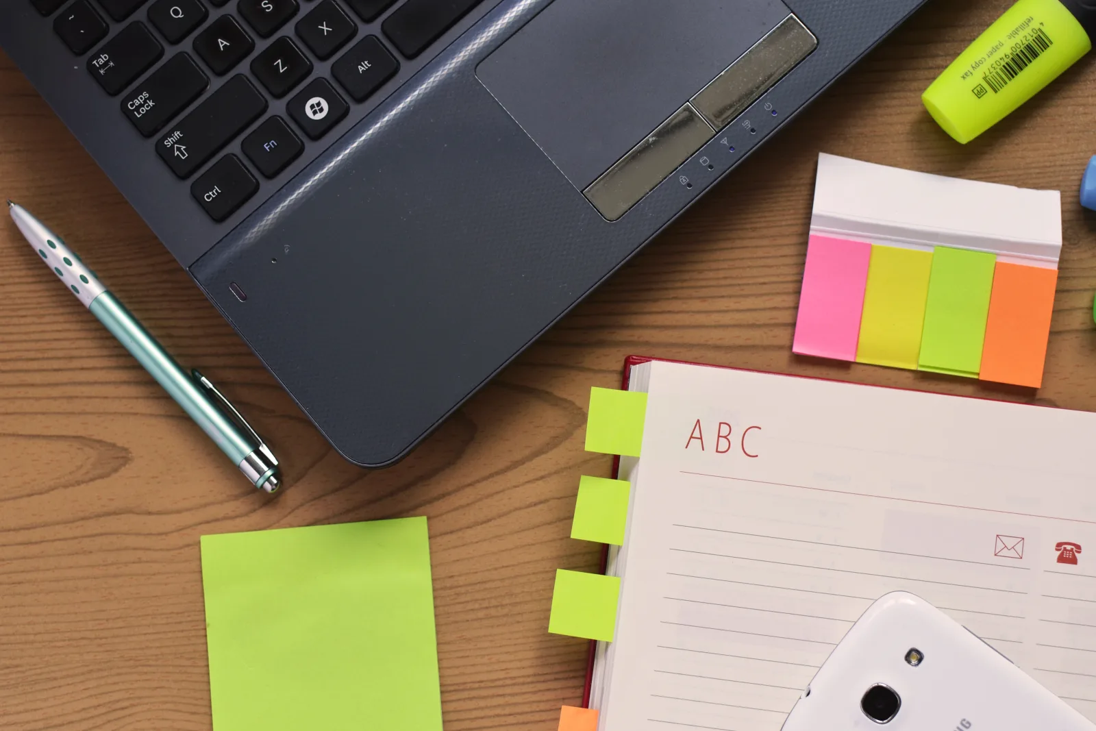 Laptop, notebook, and sticky notes on a desk, representing a seed-stage SaaS company planning a monthly cash flow forecast